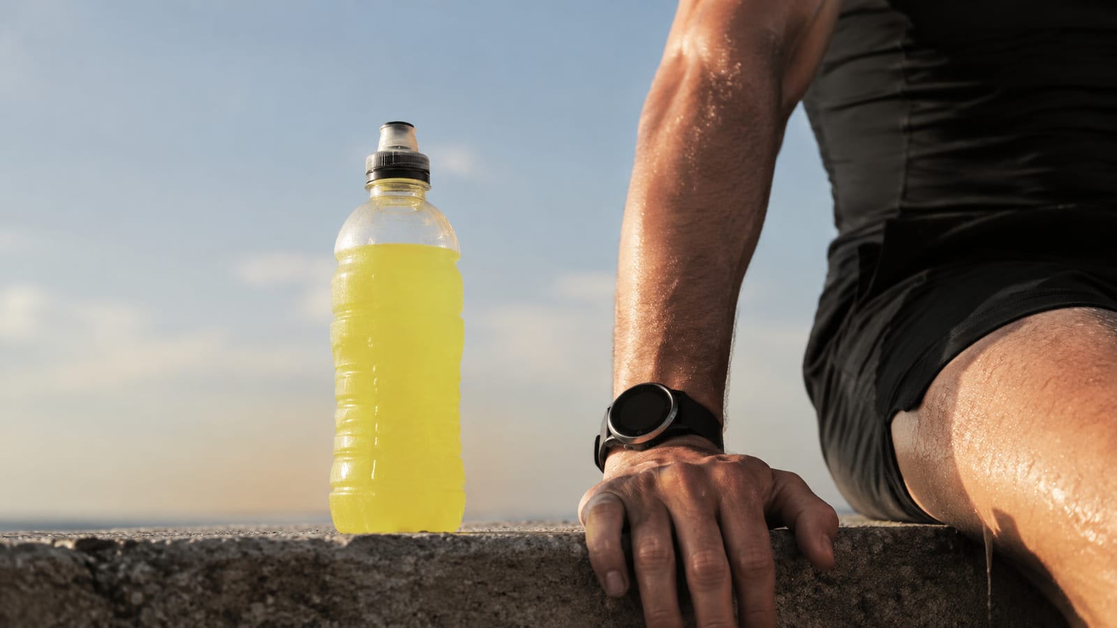 Sweaty runner from behind wiping forearm beside an unlabeled hydration bottle