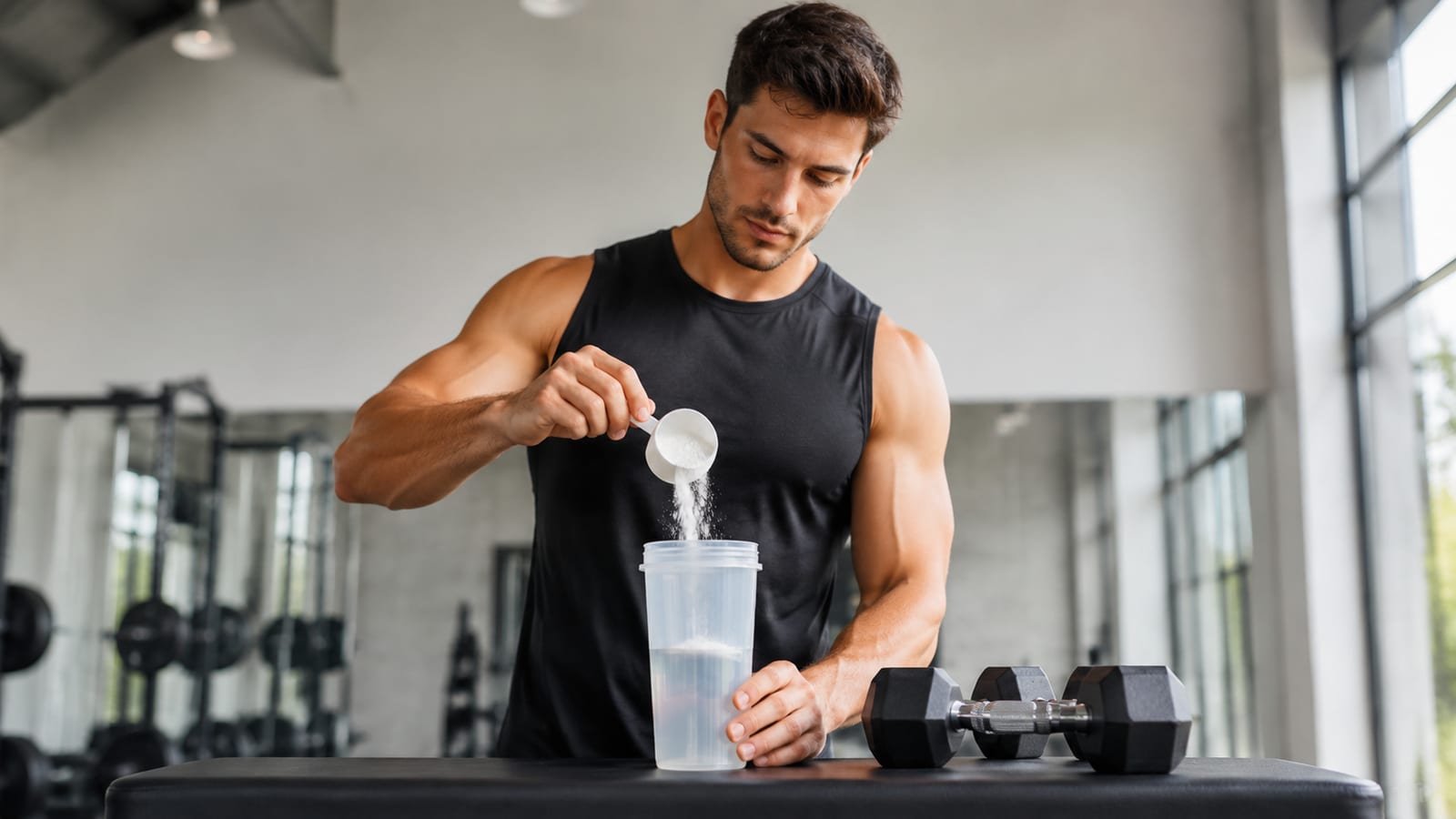 Athlete preparing creatine beside water bottle before strength training session