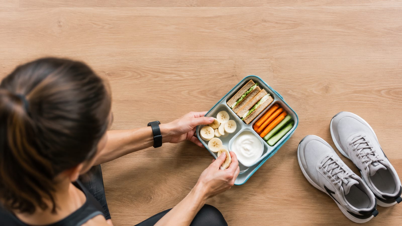 Runner packing a portable banana, sandwiches, and yogurt for recovery after a morning workout