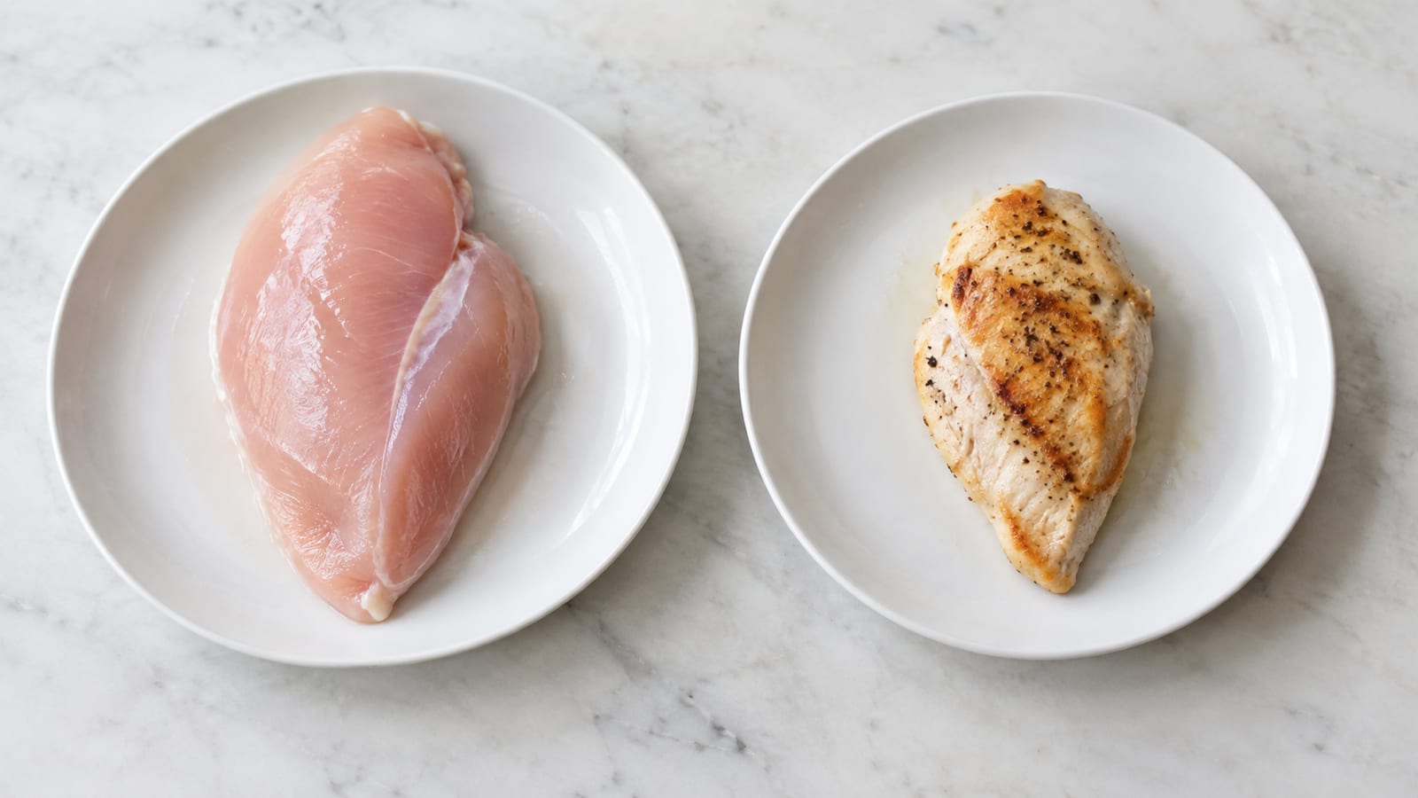 Raw and cooked chicken breasts on two white plates on a marble countertop